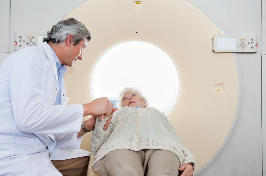 Radiologe beruhigt ältere Patientin vor einer CT-Untersuchung